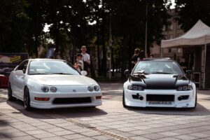 Showcase of modified Honda cars at an urban auto event with people in view.