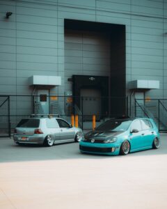 Two modified cars parked outside an industrial building. Perfect shot for urban automotive themes.